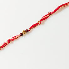 Load image into Gallery viewer, Handmade Rakhi with red and beige thread with chandan bead and gold plating