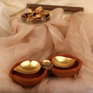 Gold plated metal diya duo encompassed by earthy terracotta