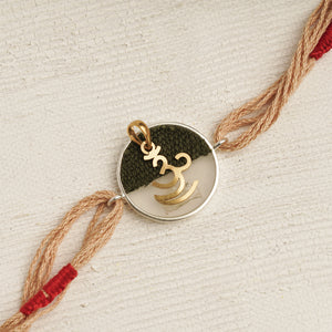 22K Gold Om Rakhi on Acrylic with brown & red thread changeable into a pendant