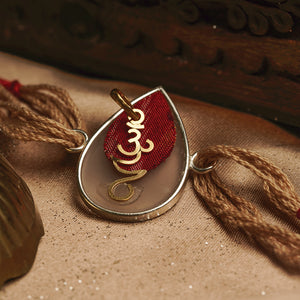 22K Gold Om Rakhi on Acrylic drop with red & brown thread changeable into a pendant
