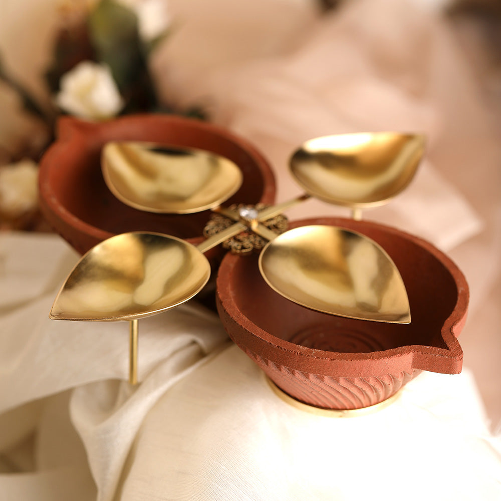 Decorative open gold plated metal diya encompassed by earthy terracotta with filigree embellishment