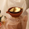 Gold plated metal diya encompassed by earthy terracotta with ornate floral detailing